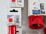 four red holesaws are sitting on a white surface next to a package of red holesaws