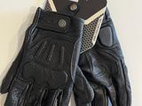 a close up of a pair of black leather gloves on a white surface