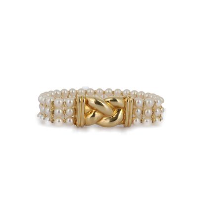 un gros plan d'une bague en or ornée de perles sur fond blanc