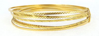 a close up of a stack of gold bracelets on a white surface