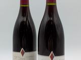 deux bouteilles de vin rouge posées l'une à côté de l'autre sur une surface blanche
