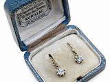 une photo d'une paire de boucles d'oreilles en diamant dans un écrin bleu