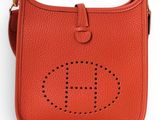 a red leather cross body bag with the letter h on it