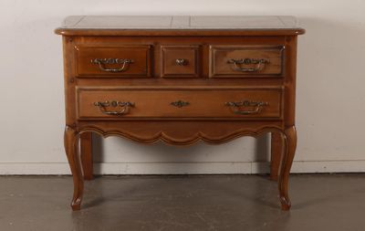 a wooden chest of drawers with marble top in a room