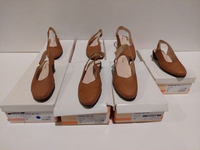 quatre paires de chaussures pour femmes dans leurs boîtes, posées sur une surface blanche