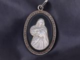 a silver pendant with a black and white image of a woman holding a child