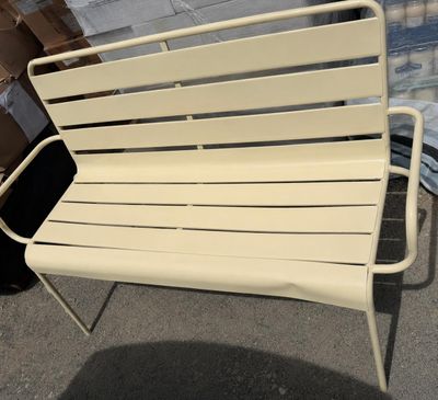 a white bench that is sitting on the sidewalk