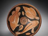 une assiette noire et orange sur laquelle sont représentés un oiseau et un poisson