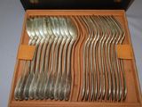 a lot of silverware in a wooden box on a table