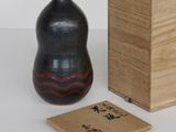 un vase noir et une boîte en bois posés sur une surface blanche
