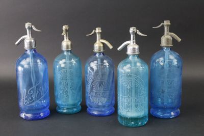 quatre bouteilles en verre bleu avec des bouchons en argent et un bec verseur en argent