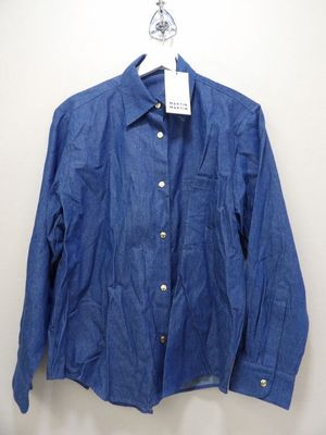 the blue shirt is hanging on a hanger on the wall