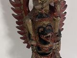 wooden statue of a man holding a bird on a blue table