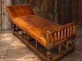 un banc en bois avec une assise en cuir marron, placé face à un mur