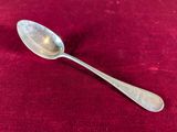 a silver spoon with a spoon handle on a red cloth