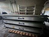 four metal trays stacked on top of each other in a warehouse