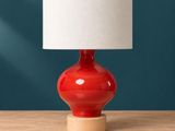 un gros plan d'une lampe de table rouge posée sur une table en bois