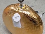 a shiny gold object on the ground next to a pair of shoes