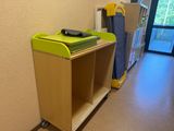 a green trash can sitting on top of a wooden shelf