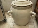 a large white pot sitting on the floor next to a stove
