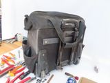 a black bag with tools on a table next to a pair of pliers and a pair of pliers