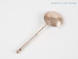 a silver spoon with a handle on a white surface