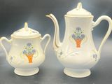 two white teapots with flowers on them on a table