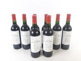 six bottles of red wine lined up in a row on a white surface
