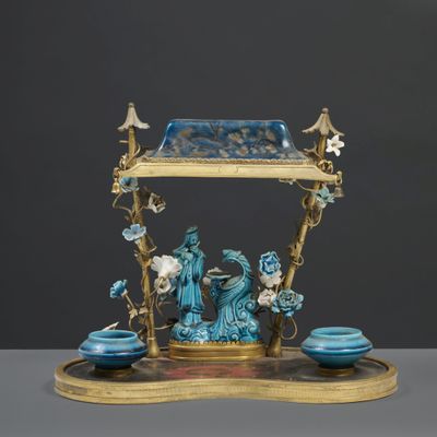 une image représentant une figurine bleue et dorée posée sur un socle