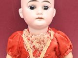a doll that is sitting on the floor with a red dress