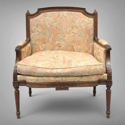 une vieille chaise avec un dossier recouvert d'un tissu à motifs floraux et un cadre en bois