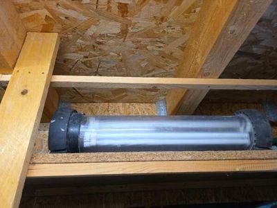 un tuyau métallique posé sur une étagère en bois dans une pièce