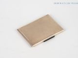 a small metal box with a pen in it on a white surface
