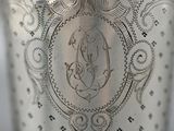 a close up of a silver vase with a monogram on it