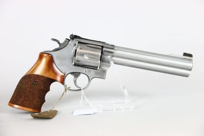 a close up of a revolver with a wooden handle on a white surface