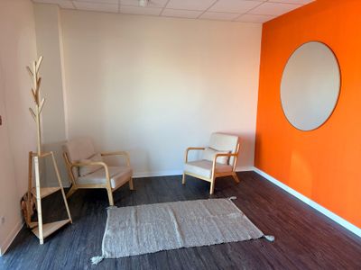 une pièce avec une chaise, un miroir, un tapis et un miroir accroché au mur