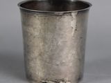 an old silver cup sitting on top of a table next to a gray background