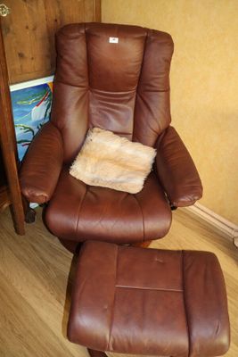 fauteuil inclinable en cuir marron et repose-pieds dans une pièce avec du parquet