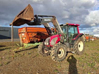 un tracteur qui est à l'arrêt dans la terre, près d'un camion-benne