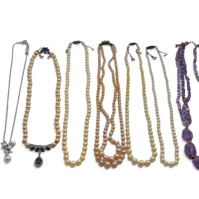 several necklaces of various shapes and colors are arranged on a white surface