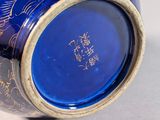 a blue vase with gold decoration on it on a white surface