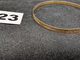 un gros plan d'un bracelet en or sur lequel figure le chiffre 23
