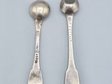 two silver spoons and a spoon on a white surface