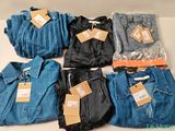 Plusieurs paires de jeans et chemises pour hommes sont posées sur une table