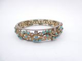 a close up of a gold and turquoise bracelet on a white surface