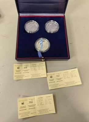 two silver coins are in a box with a ribbon around them