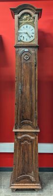 une grande horloge de parquet en bois devant un mur rouge
