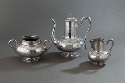 trois théières en argent et deux tasses en argent posées sur une table