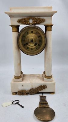 une petite horloge posée sur une table à côté d'une paire de ciseaux
