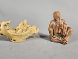 deux figurines sculptées représentant un homme assis sur un bateau et un homme assis sur un bateau
